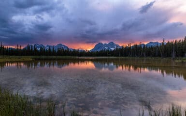 The sun sets over a pond in Spray Valley Provincal Park in Alberta, Canada.